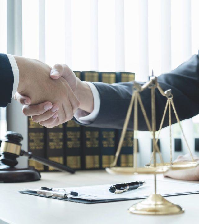 Handshake after Lawyer  providing legal consult business dispute service to the man at the office with justice scale and gavel hammer.